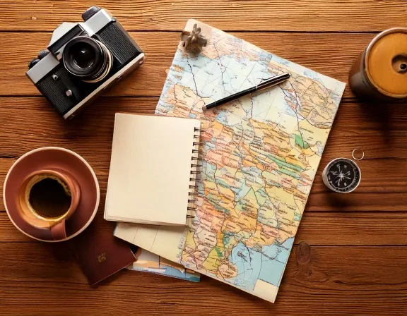 地図・ノート・カメラ・コーヒーを並べた旅の準備